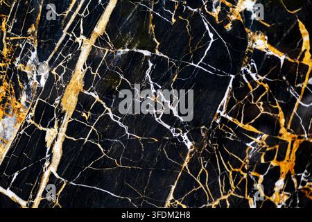 Struttura di marmo nero con venature dorate e bianche. Primo piano di marmo nero lucidato con venature dorate e bianche drammatiche, crepe fini e irregolari Foto Stock
