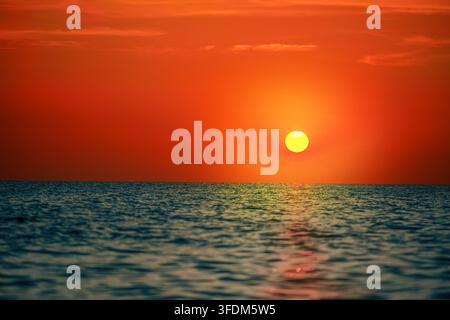 Tramonto arancione sull'orizzonte dell'oceano con mare calmo Foto Stock