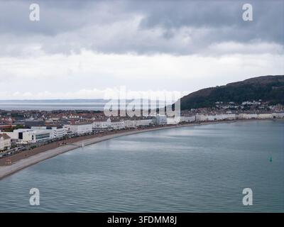 Foto aerea di Llandudno in estate con vista sulla curvata passeggiata sul mare del Galles del Nord con edifici costieri, baia calma, collina di Great Orme e dram Foto Stock