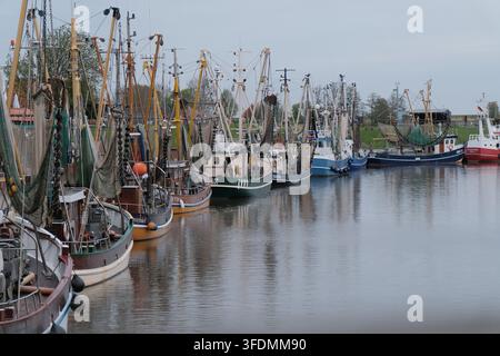 Tagliac gamberetti tradizionali in legno con reti da pesca verdi ormeggiate fianco a fianco nel porto di marea di Greetsiel, Ostfrisia, Bassa Sassonia, Germania, A Foto Stock