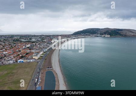 Foto aerea di Llandudno in estate che mostra il lungomare esteso del Galles del Nord con la passeggiata sul lungomare di ciottoli, gli edifici costieri, la baia calma e il promontorio di Great Orme Foto Stock