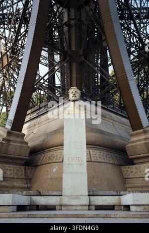 Busto di Gustave Eiffel in bronzo dorato su una base in pietra naturale chiara, posizionato direttamente ai piedi della storica struttura in ferro Foto Stock