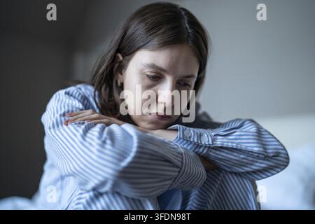 La donna esausta e depressa siede in pigiama si sente inmotivata, frustrata per la vita persa in pensieri negativi. Donna triste sopraffatta da disturbi mentali Foto Stock