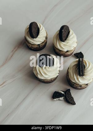 Mini cheesecake Oreo con panna montata e biscotti al cioccolato su tavolo di marmo chiaro, vista ad angolazione alta Foto Stock