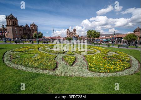 Vivace Plaza de Armas a Cusco, Perù, con un'aiuola decorativa, una cattedrale coloniale, edifici storici e una vivace piazza pubblica in una giornata di sole Foto Stock