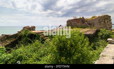 Una vista diurna di una struttura in pietra e cemento abbandonata e in rovina situata direttamente su una costa. L'edificio fatiscente presenta pietra sgretolante Foto Stock