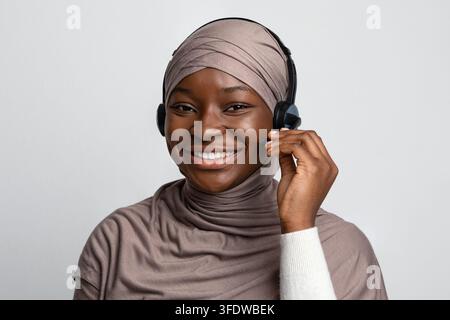 Posti di lavoro per le donne musulmane. Ritratto di Black Lady in Hijab e cuffie Foto Stock