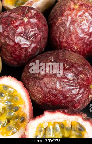 Frutti della passione interi e affettati, maturi, su sfondo scuro, primo piano. Foto Stock