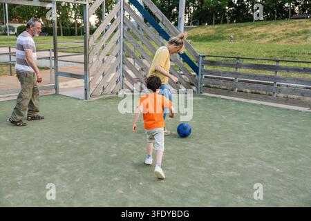 Famiglia multigenerazionale che gioca a calcio nel parco Foto Stock