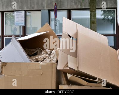 Vista dettagliata di scatole di cartone piegate e materiale di riempimento in carta ammucchiati su una strada pubblica. Perfetto per temi riguardanti la gestione dei rifiuti, Riciclaggio Foto Stock