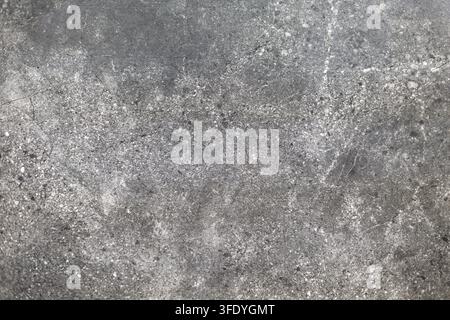 Textura di pietra grigio scuro con macchie bianche. Primo piano di pietra grigio scuro con macchie bianche, graffi e una texture superficiale screziata. Foto Stock