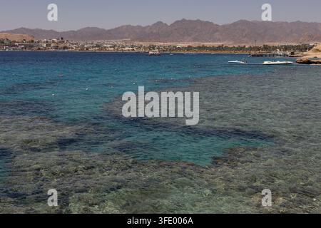 Acqua turchese chiara su una barriera corallina poco profonda vicino al Movenpick Resort Sharm El Sheikh, Egitto, con la costa del Mar Rosso in lontananza Foto Stock