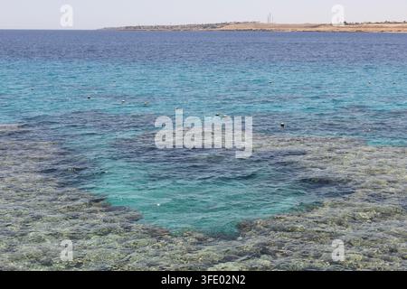 Acqua turchese chiara su una barriera corallina poco profonda vicino al Movenpick Resort Sharm El Sheikh, Egitto, con la costa del Mar Rosso in lontananza Foto Stock