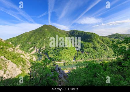 Catena montuosa con un fiume che la attraversa. Il cielo è sereno e blu. Le montagne sono rigogliose e verdi Foto Stock