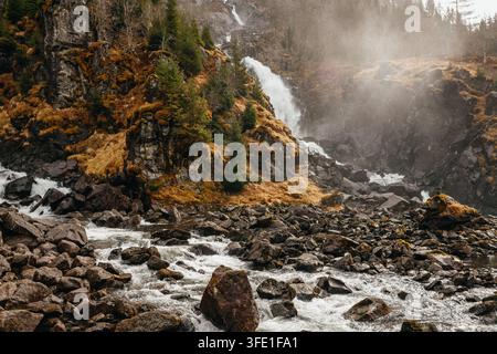 Una vista autunnale cupa e drammatica della famosa cascata di Latefossen che scorre sotto un ponte ad arco in pietra storico sulla Strada 13 in Norvegia. Foto Stock
