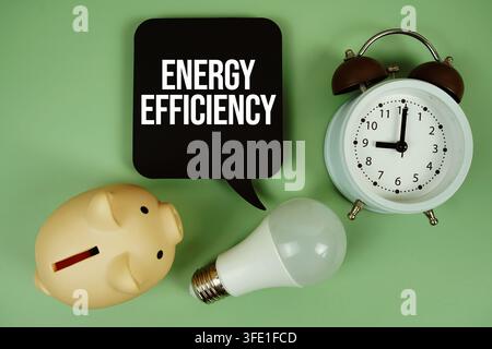 Testo sull'efficienza energetica con lampadina e sveglia su sfondo verde Foto Stock