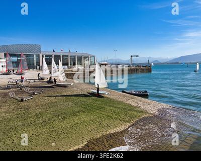 Scuola di vela alla marina - Giovani velisti che preparano piccoli velieri per una sessione di allenamento in una giornata di sole vicino a un moderno club nautico in una costa scenografica Foto Stock