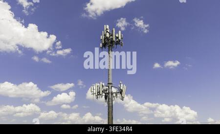 Vista aerea di un singolo traliccio per cellulari con più antenne contro un cielo blu brillante con nuvole bianche sparse a Nashville, Tennessee, Stati Uniti Foto Stock