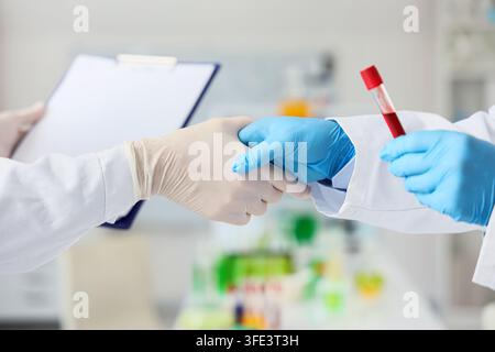 Chimici che si stringono la mano in laboratorio, primo piano Foto Stock