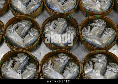 Tre piccoli pesci di sgombro cotti al vapore in un cestino di bambù intrecciato tradizionale al mercato di Mae Klong, Thailandia, una prelibatezza locale di frutti di mare. Foto Stock