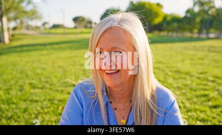 Anziana sorridente che gode di una giornata estiva nel parco Foto Stock