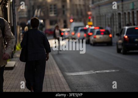 Passare in bicicletta davanti al traffico fermo è uno dei piccoli vantaggi quotidiani del pendolare urbano, un ciclista che si intrufola tra le auto ferme mentre Riga si svuota dopo il *** Foto Stock