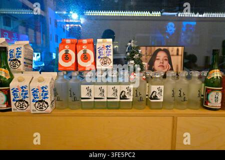 Una esposizione di bevande coreane assortite tra cui bottiglie di soju e cartoni di latte in un ambiente di bar coreano. Foto Stock