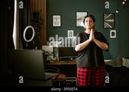 Donna biracial che pratica yoga durante una lezione online a casa Foto Stock