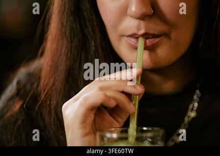 Donna che beve un frullato fresco con una cannuccia riutilizzabile Foto Stock