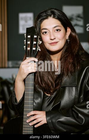 Ritratto di una donna birazziale che tiene una chitarra in uno studio di musica Foto Stock
