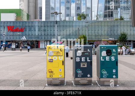 Tre bidoni di riciclo di colori diversi in piedi davanti al centro commerciale 'les 4 Temps' nel distretto commerciale e finanziario di La Défense Foto Stock
