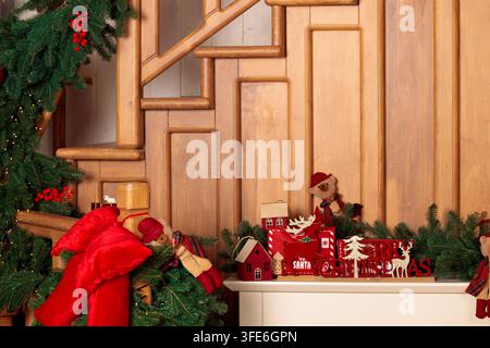 Scena natalizia calda e accogliente con una scala di legno rustica adornata da ghirlande di sempreverdi e affascinanti decorazioni festive Foto Stock