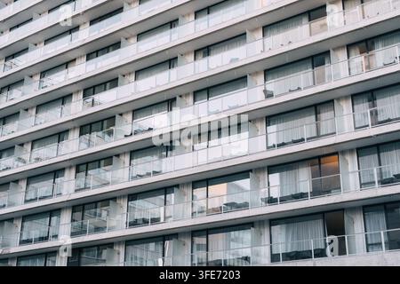 Facciata di balcone moderna, densamente sfalsata di un edificio residenziale a più piani, hotel o complesso di appartamenti con ringhiere in vetro e grandi vetrate Foto Stock
