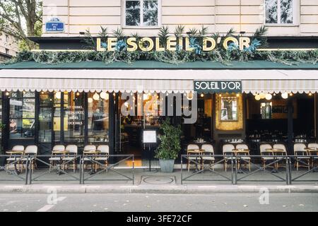 Vista stradale della facciata d'ingresso, ristorazione all'aperto al ristorante Le Soleil d'Or con una terrazza a sedere nello stile tipico del caffè di strada francese Foto Stock