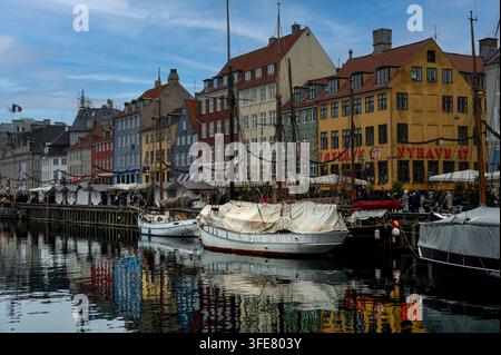 Copenaghen, Danimarca – dicembre 2025: navi a vela storiche sono ormeggiate lungo il canale Nyhavn, riflesse nell'acqua davanti alle case dai timpani colorati Foto Stock