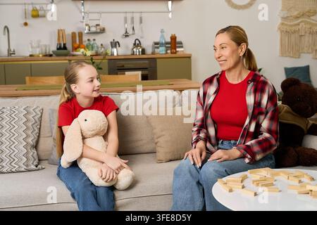 Una madre e una figlia condividono momenti gioiosi sul divano, rafforzando un legame d'amore Foto Stock
