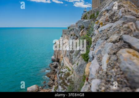 Sentiero su roccia e faro lungo le imponenti mura fortificate rivolte verso il mare del castello di Peñíscola, Spagna. Foto Stock