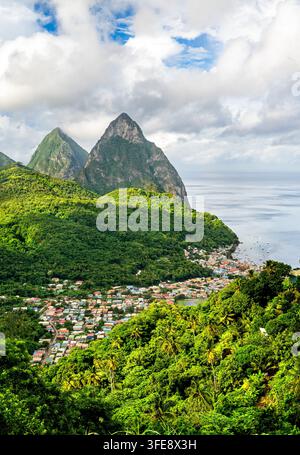 Vista aerea scenografica della città di Soufriere, della rigogliosa foresta tropicale verde e delle iconiche guglie vulcaniche dei Pitons lungo la costa di Santa Lucia, Caraibi Foto Stock