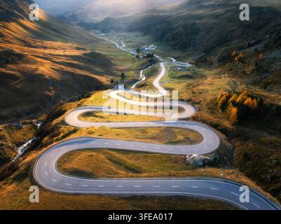 Vista aerea della tortuosa strada di montagna, fiume nella valle alpina Foto Stock