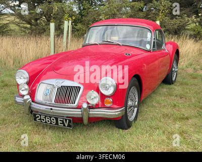 Coupé MG MGA rosso parcheggiato nella campagna del Regno Unito durante una mostra di auto classiche Foto Stock