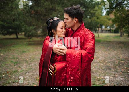 Coppie interrazziali che abbracciano, celebrano il loro amore multiculturale e il loro matrimonio in abiti tradizionali cinesi Foto Stock