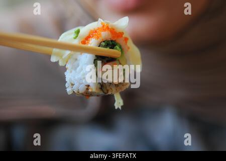 Mangiare sushi con bacchette in un ambiente informale Foto Stock