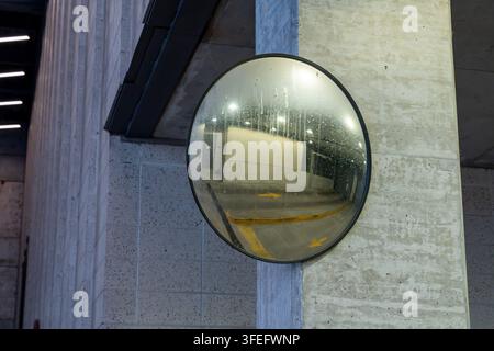 Specchio convesso per il traffico installato vicino all'uscita di un garage, che offre un campo visivo più ampio a conducenti e pedoni, migliorando la visibilità e la sicurezza stradale Foto Stock