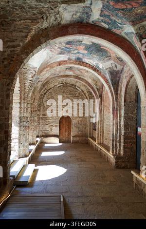 All'interno di un antico corridoio di pietra, la luce del sole si riversa sul pavimento di pietra, evidenziando i dettagli architettonici e le opere d'arte. Foto Stock