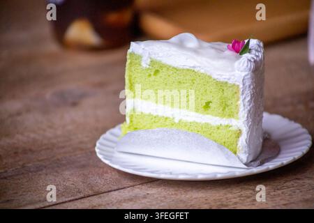 Torta chiffon al cocco fresca di forno servita su un piatto di porcellana bianca, con una consistenza morbida e ariosa. Immagine di dessert ad alta risoluzione isolata Foto Stock