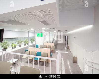 Spazio clinico contemporaneo con area d'attesa, sedute e un lungo corridoio illuminato Foto Stock