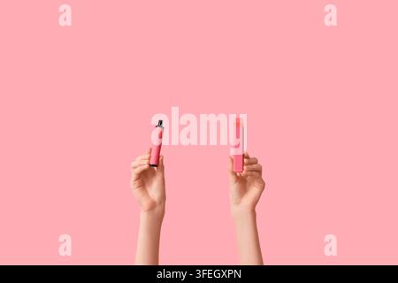 Mani che tengono sigarette elettroniche su sfondo rosa Foto Stock