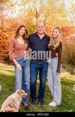 Padre con due figlie adulte che sorridono per un ritratto Foto Stock