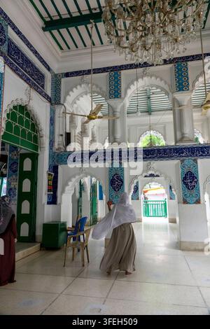Donna con uno scialle bianco che cammina attraverso un corridoio ad arco del santuario di Hussaini Dalan, Divisione di Dhaka, Dhaka, Bangladesh Foto Stock