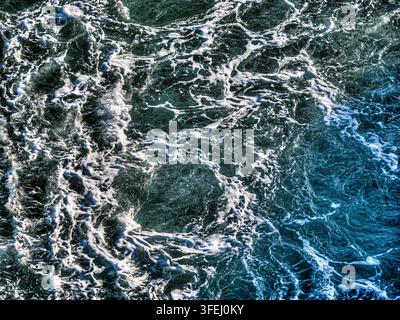 Onde dell'oceano che si infrangono e creano schiuma bianca e motivi astratti dell'acqua. Texture astratta di mare blu e verde Foto Stock